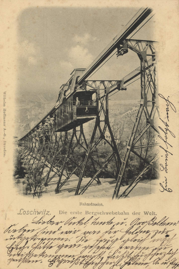 Ein altes Schwarz-Weiß-Foto einer Eisenbahnbrücke mit einem Kran darauf, umgeben von Bäumen und einem bewölkten Himmel, mit dem Text "Bahnstrecka, die erste Eisenbahnbrücke in Deutschland" unten.