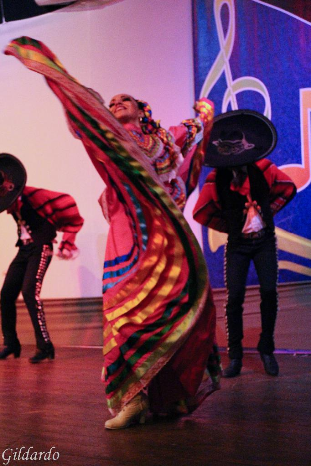 Leute auf einer Bühne in Kostümen stehend, mit einem Vorhang mit einem Bild im Hintergrund.