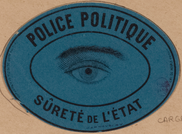 Ein brauner Karton mit einem blauen Aufkleber, der "Polizei Politique Süret√© de l√Čtat" und ein Auge in der Mitte carries.