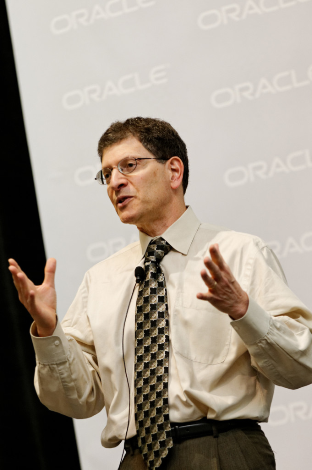 Eine Person steht vor einer Sponsorwand und trägt Kleidung und eine Brille.