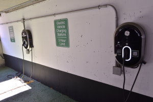 Zwei Elektrofahrzeug-Ladestationen an einer Wand in einer Tiefgarage, mit Informationsschildern und einem sichtbaren Boden.