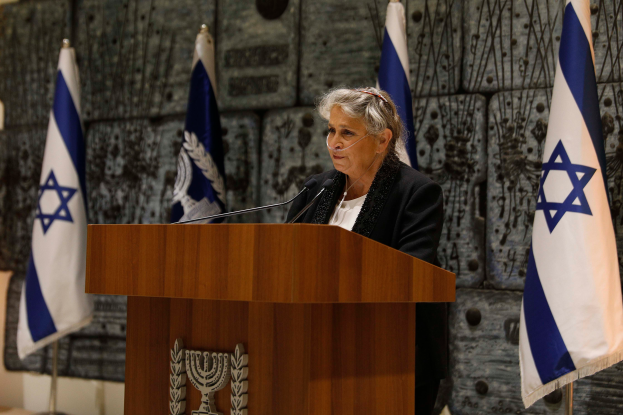 Israeli Premierminister Yitzhak Rabin in einem schwarzen und weißen Kleid vor israelischen Flaggen an einem Podium mit mehreren Mikrofonen stehend, der in Jerusalem vor einer Wand spricht.