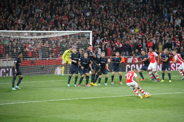 Fuballspieler auf einem Feld mit einer groГџen Menge im Hintergrund.